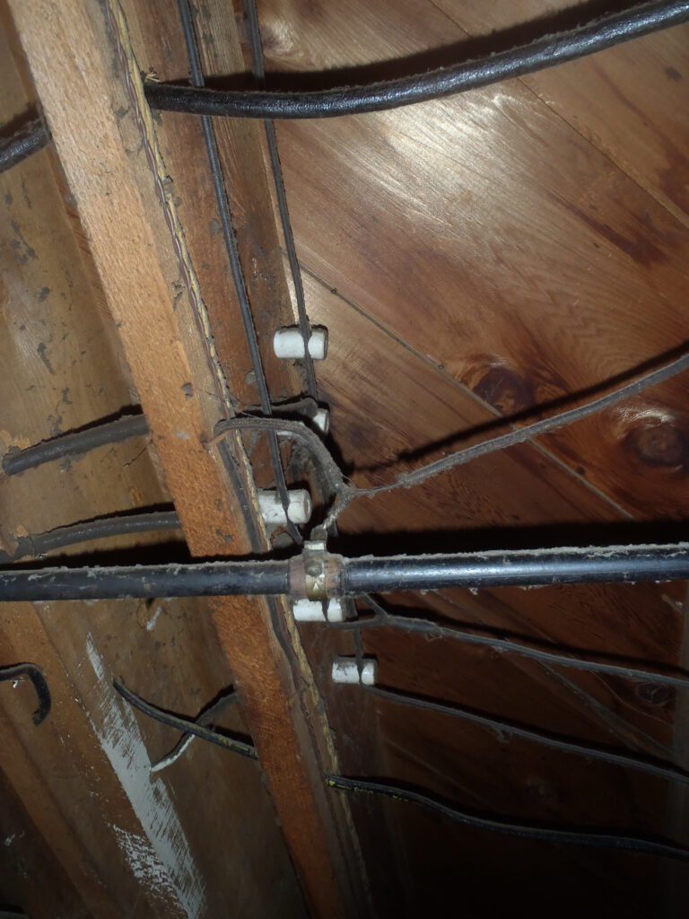 Knob and tube wiring system in an older home showing exposed electrical wiring and ceramic supports.